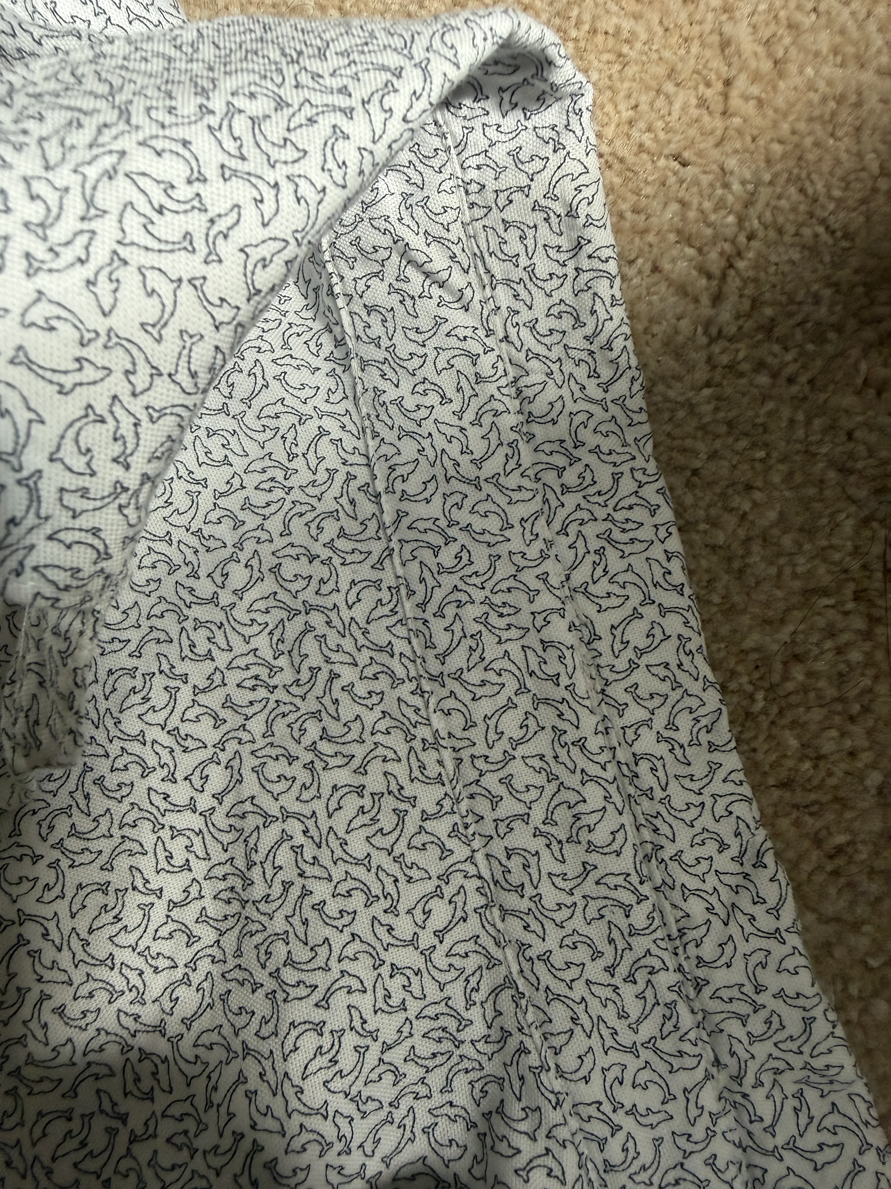 Inside of the shirt showing a finished flat-fell seam — the seam allowance fully enclosed and topstitched flat across the dolphin-print cotton