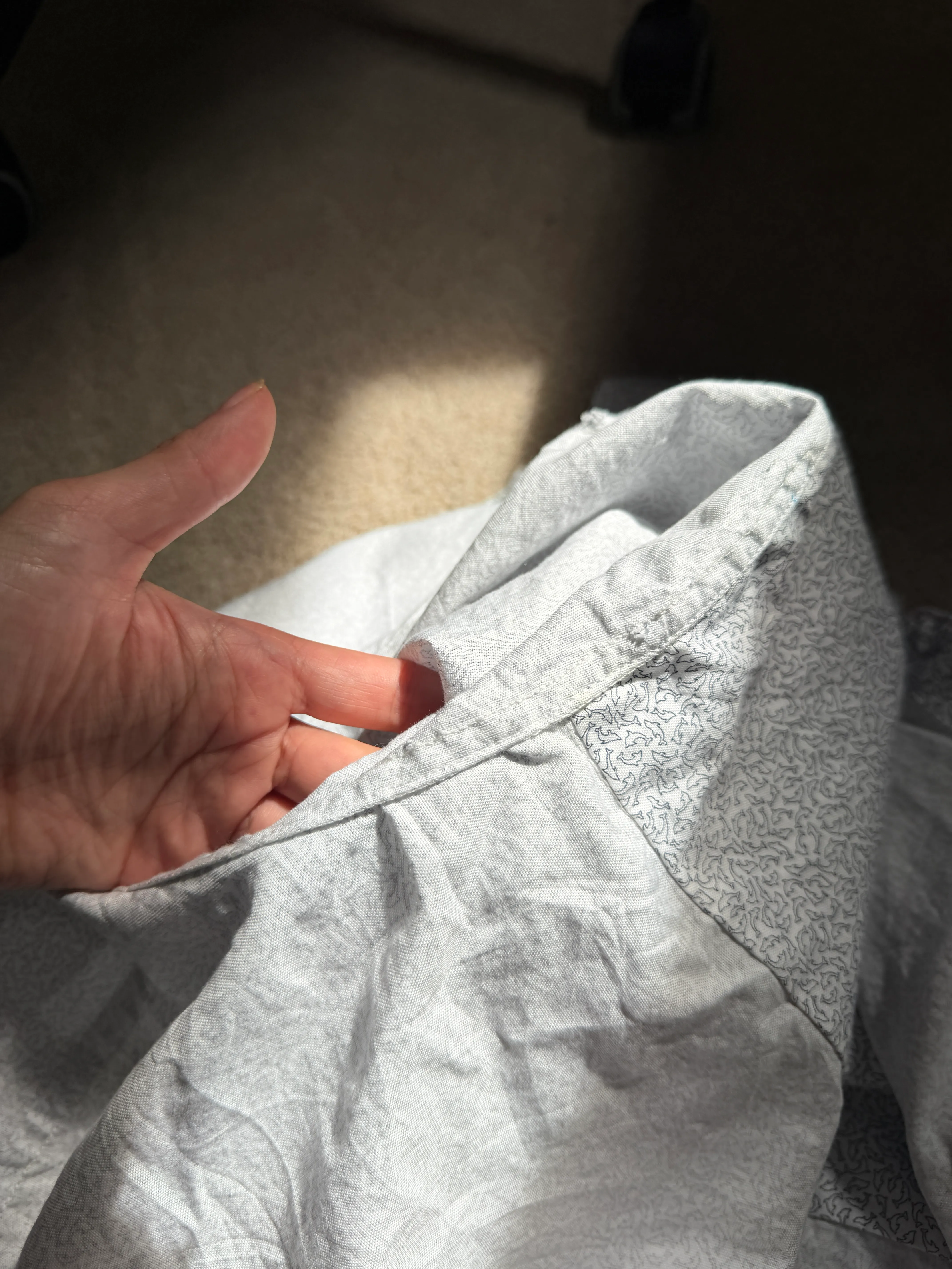 Holding the side seam open to show the clean enclosed wrong side of the flat-fell seam, in raking light