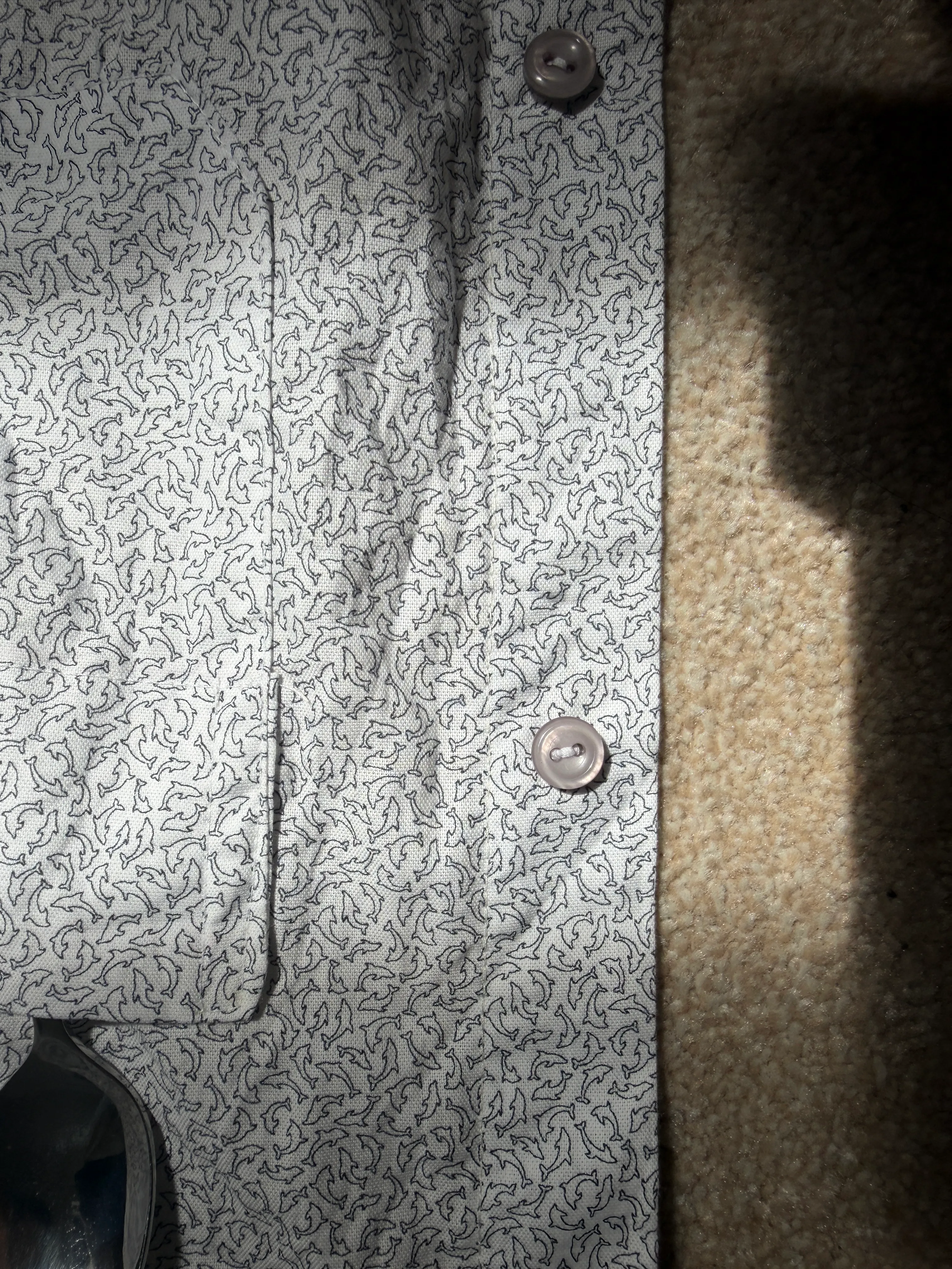 Close-up of the finished front placket and hem with two grey buttons on the dolphin-print fabric